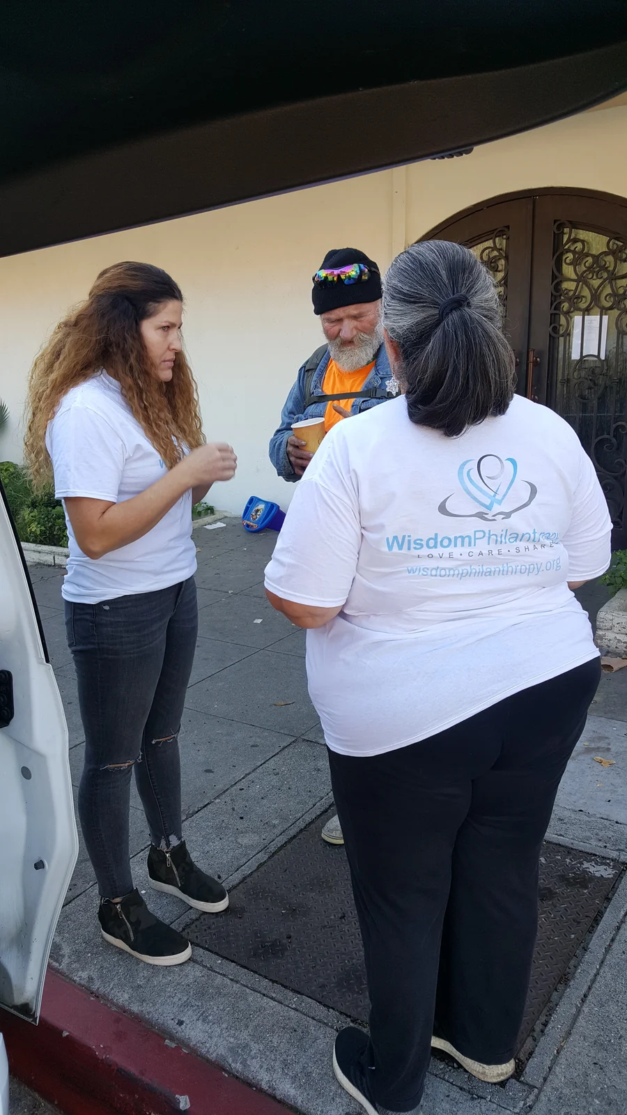 Adults wearing organizational shirts outdoors.